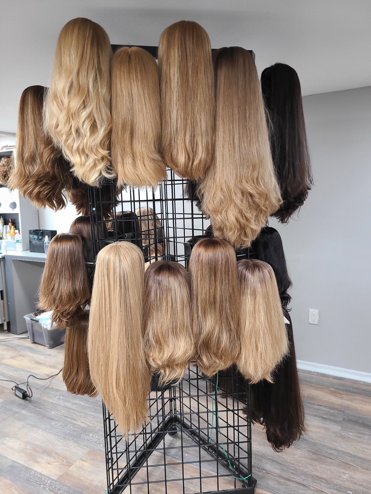 Display stand holding blonde to dark brown wigs in a salon room